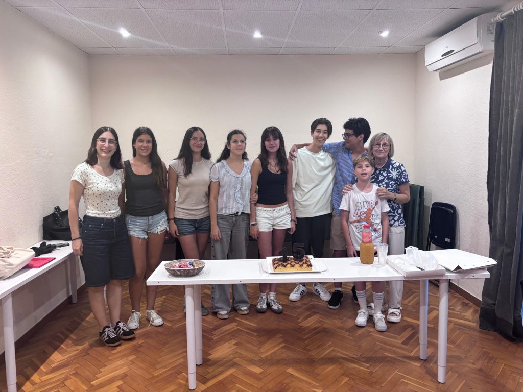 Alumnes més grans de l’escola darrere una taula amb un pastís amb les espelmes del número 15, en una aula de l’Estudi Musical 143.