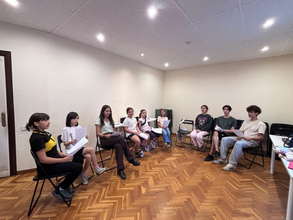 Cantaires del Cor Jove asseguts en rotllana amb les partitures, assajant en una aula de l’Estudi Musical 143.